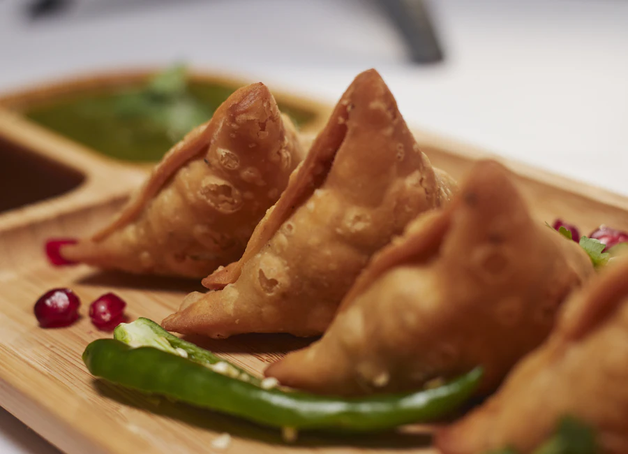 Crisp golden samosas served with green chutney and a fresh chilli